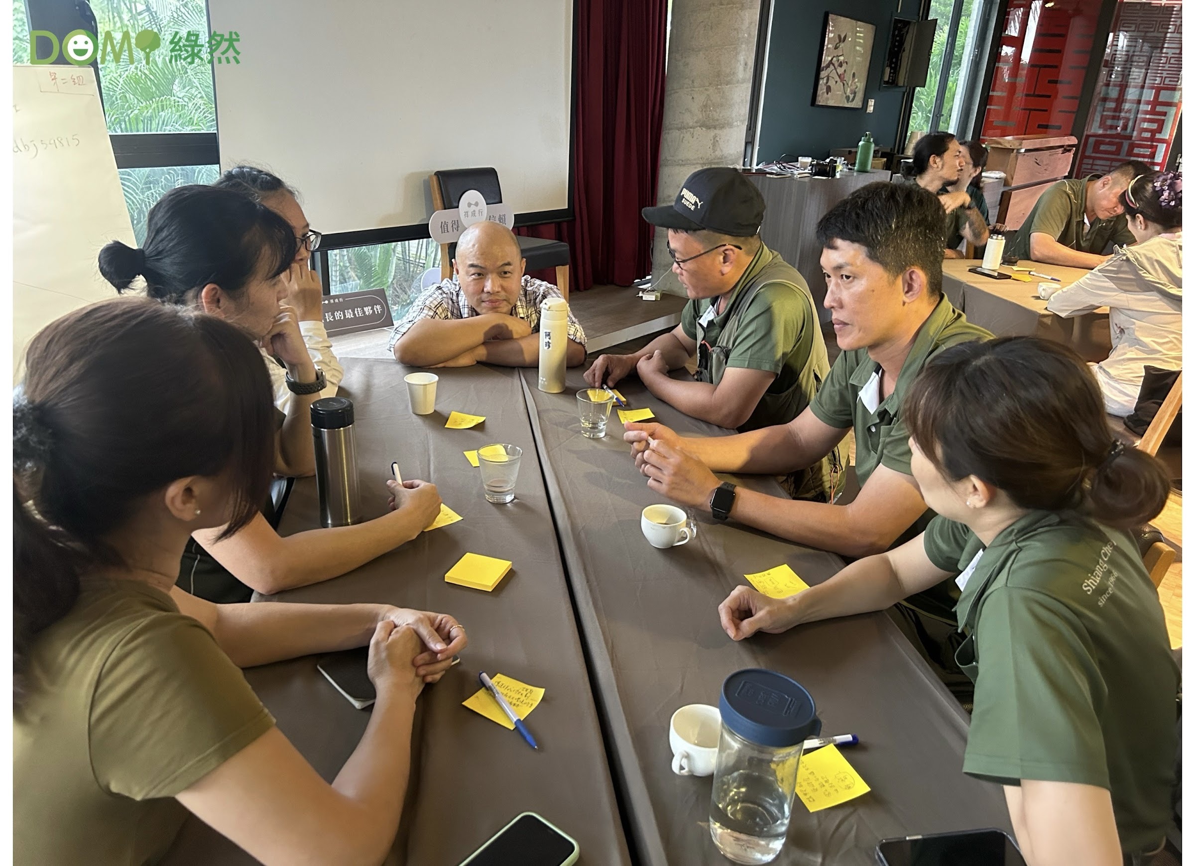DOMI 綠然與夥伴進行永續共創工作坊，眾人圍著長桌一起討論並記錄想法