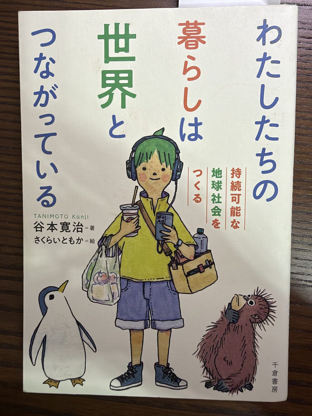 ปกหนังสือ 『わたしたちの暮らしは世界とつながっている』 โดยคันจิ ทานิโมโตะ ภาพประกอบโดยโทโมกะ ซากุไร สำนักพิมพ์ชิคุระโชโบ