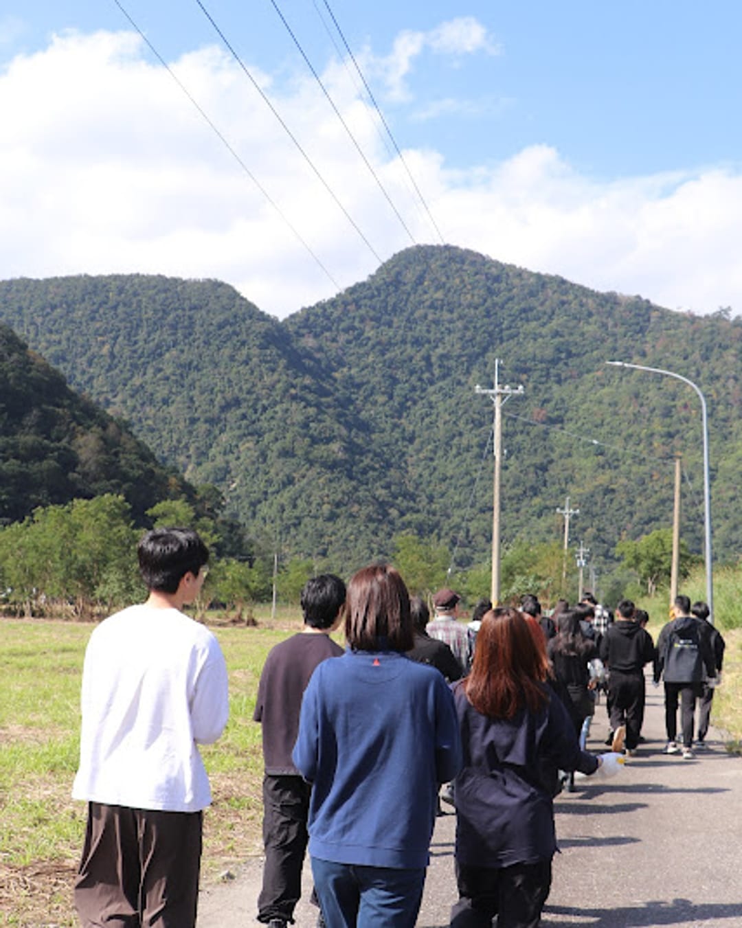Participants walking down a country path toward the mountain planting site at a joint corporate planting day
