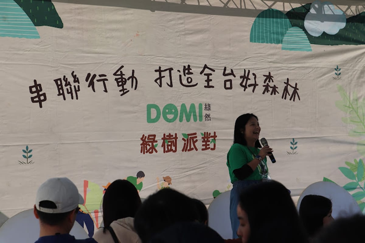 An emcee opens the day for corporate participants in front of the hand-drawn Green Tree Party backdrop