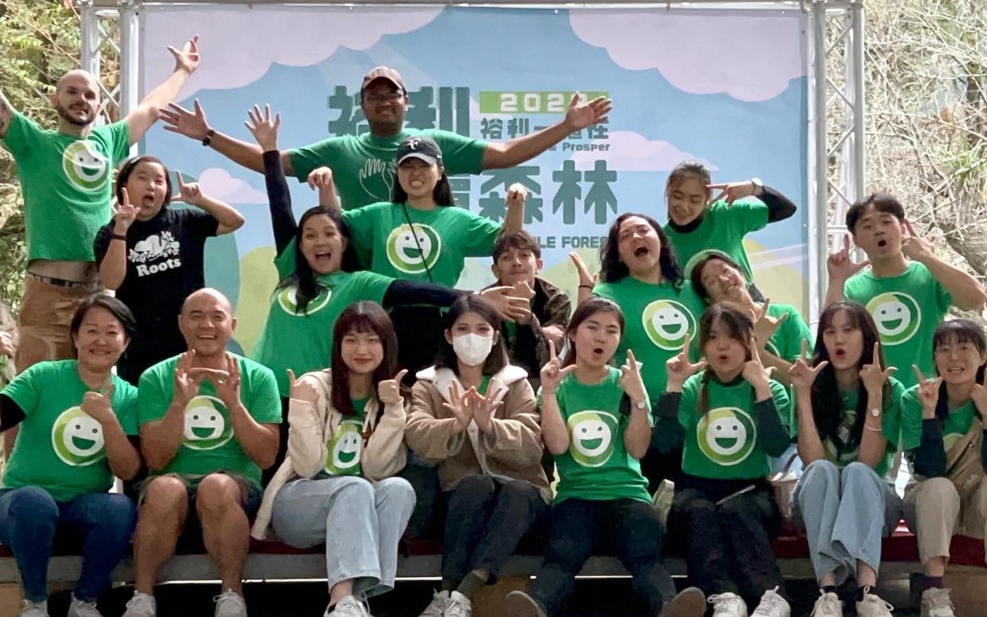 Colleagues in DOMI smiley tees cheering together at a corporate tree-planting party
