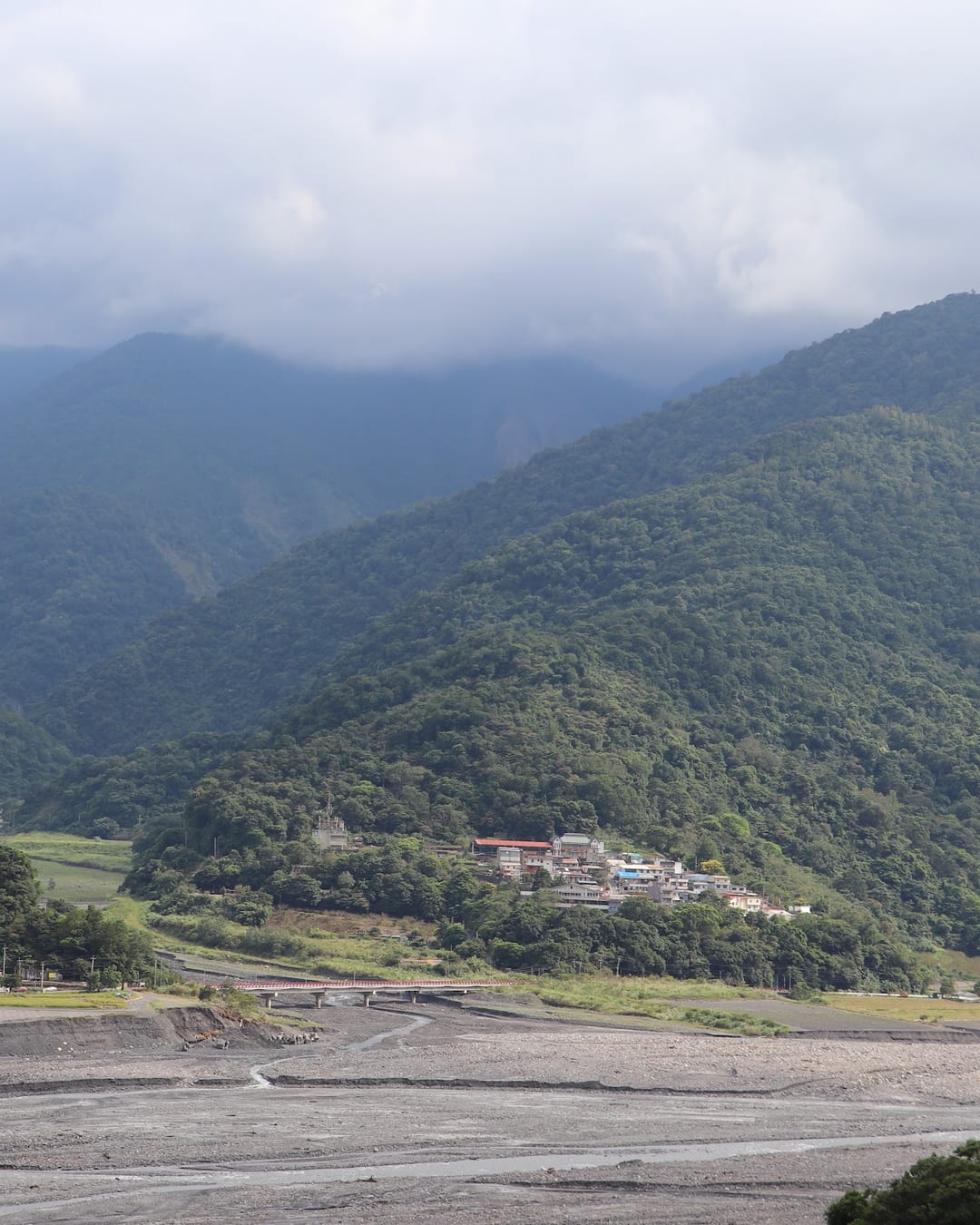 A tribal village in a mountain valley in Datong, Yilan — mist-wrapped ridges around the riverbed and hillside settlement