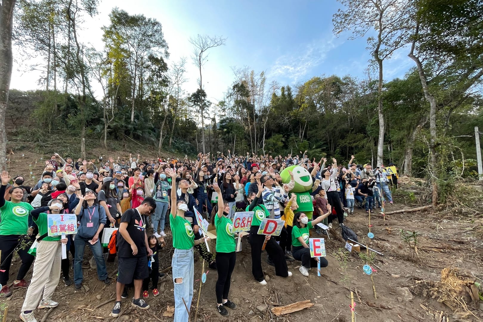 150 group employees and their families cheering together on a hillside reforestation site